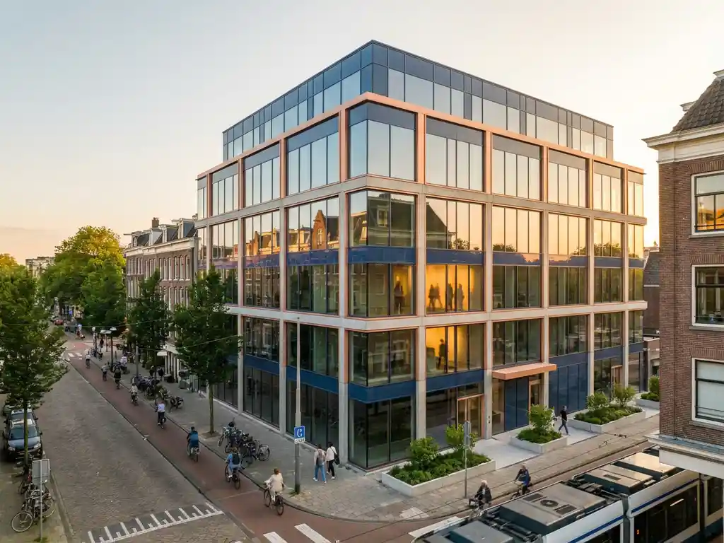 Modern glazen kantoorgebouw met warme zonlicht reflecties in het centrum van Amsterdam, omringd door bomen en fietspaden