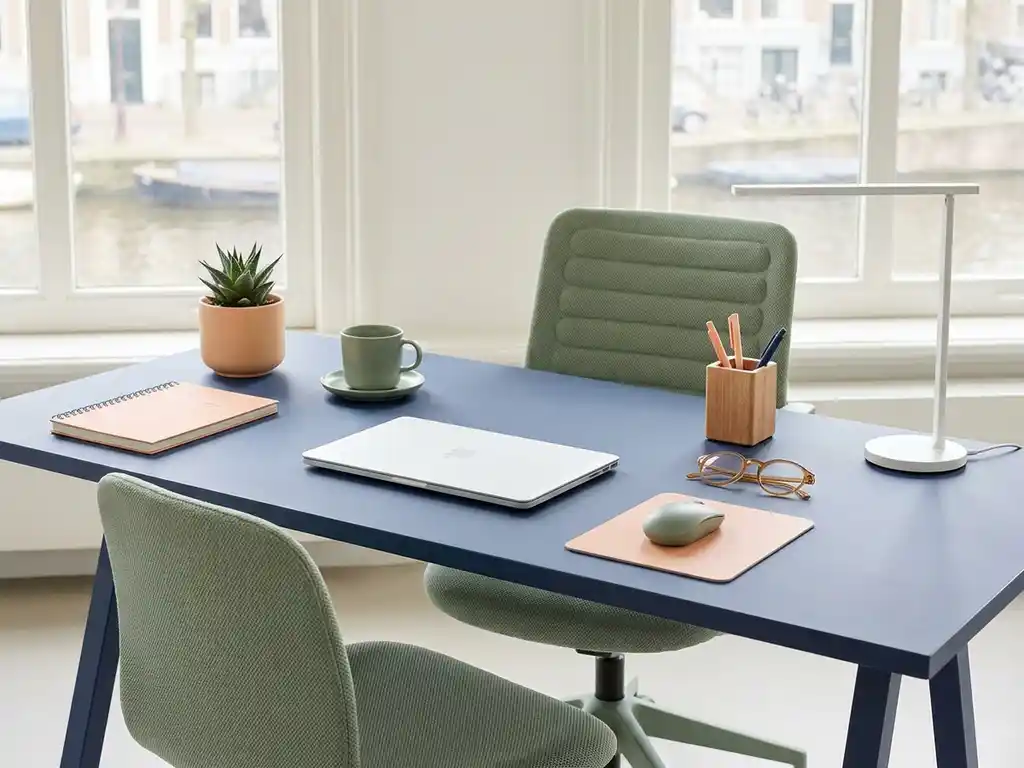 Modern kantoorwerkplek met negen bureauaccessoires in rasterpatroon op marineblauw bureau met perzik en saliegroen accenten